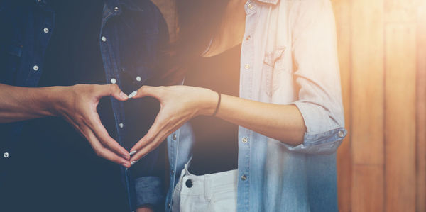 Midsection of couple making heart shape