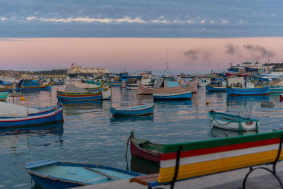 Boats moored in sea against sky during sunset