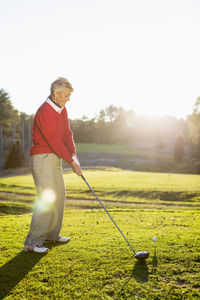 Full length side view of senior woman playing golf on course