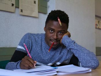 Portrait of young man studying on table at home