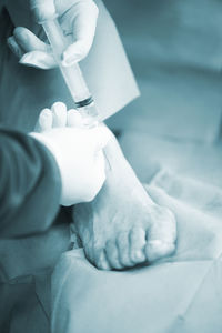 Cropped hands of doctor injecting patient at hospital