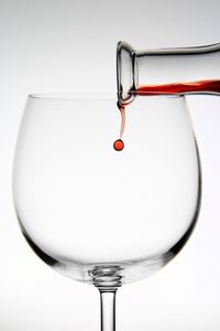 Close-up of wineglass on glass against white background