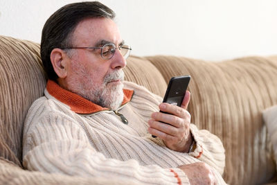 Close-up of man using mobile phone on sofa