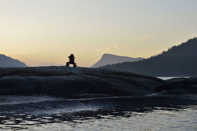 Silhouette man standing by sea against sky during sunset