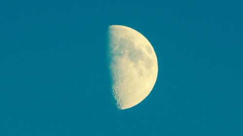 Low angle view of moon against clear blue sky