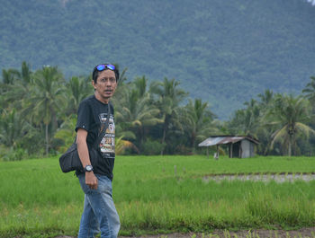 Portrait of man standing by rice paddy on farm 