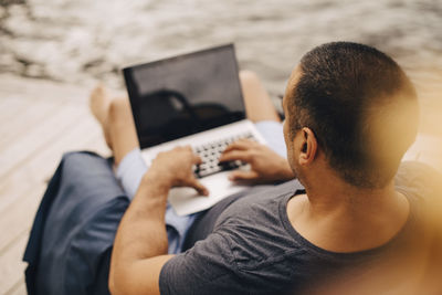 High angle view of mature man using laptop while working in summer vacation