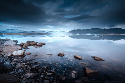 Scenic view of calm lake against cloudy sky