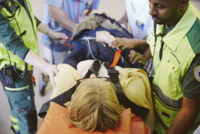 High angle view of healthcare workers consoling female patient on hospital gurney