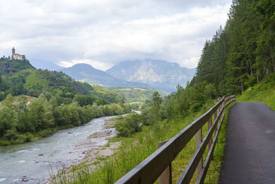 Road amidst trees and mountains against sky