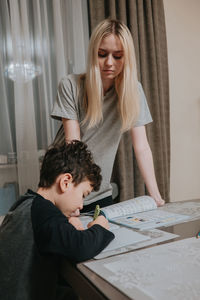 Mom and son are doing homework. sister helps brother solve math. home schooling. high quality photo