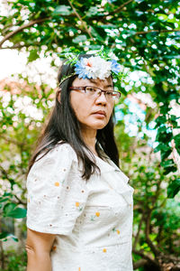 Portrait of a beautiful young woman standing against plants