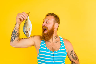 Young man holding food against yellow background