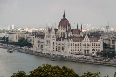 Buildings by river against sky in city