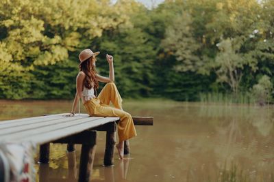 Rear view of woman standing by lake