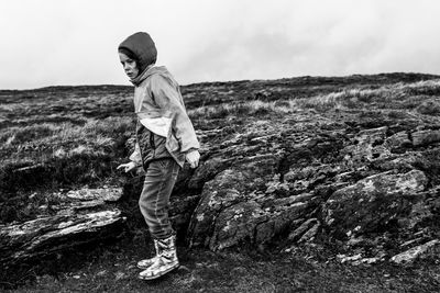 Full length of girl standing on rock against sky during winter