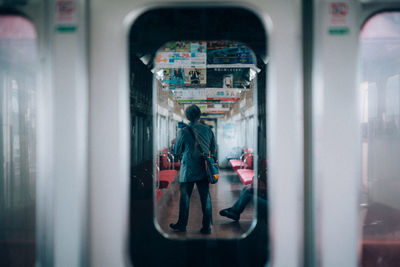 Rear view of man seen through train window