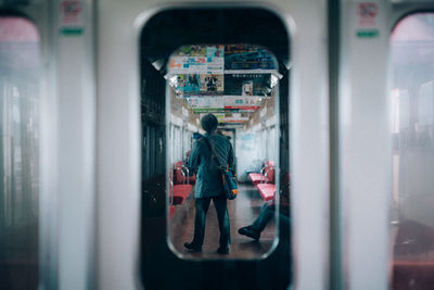 Rear view of girl standing in train