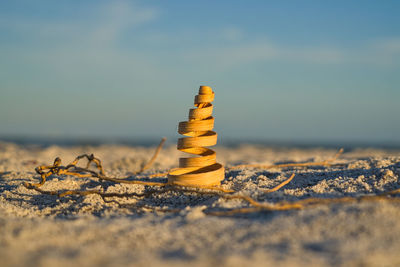 Stack of stones on sand at beach against sky