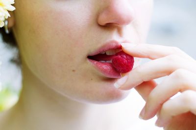 Cropped image of woman eating raspberry