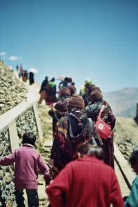 Rear view of people walking on mountain against sky