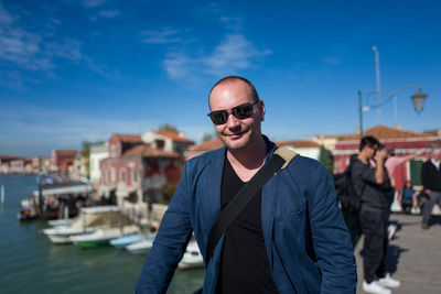 Portrait of smiling man standing at harbor against sky