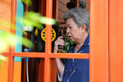 Senior woman talking on phone in telephone booth