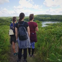 Rear view of friends standing on landscape against sky