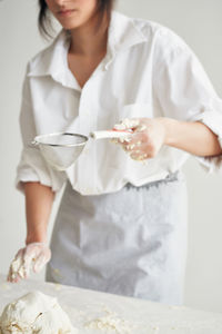 Midsection of woman kneading dough on table