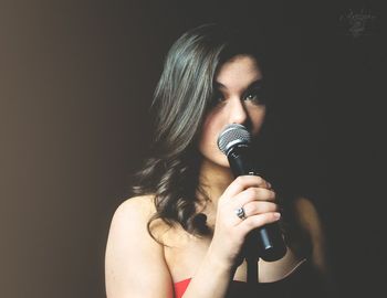 Portrait of beautiful woman holding hands against black background