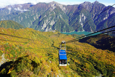 Low angle view of overhead cable car against mountain range