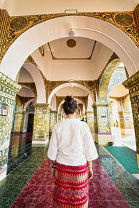 Rear view of woman walking in corridor in temple