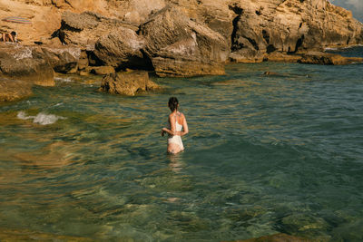 Full length of woman on rock formation in sea