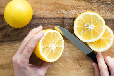 Close-up of hand holding lemon slice in cutting board