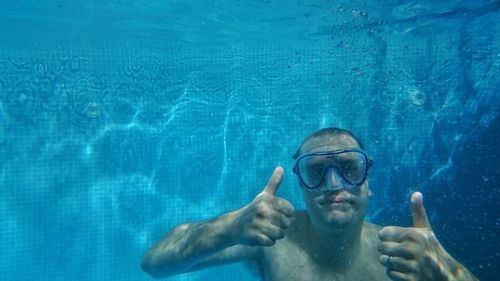 Man swimming while gesturing thumbs up sign in sea