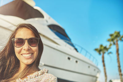 Portrait of smiling young woman in sunglasses against sky