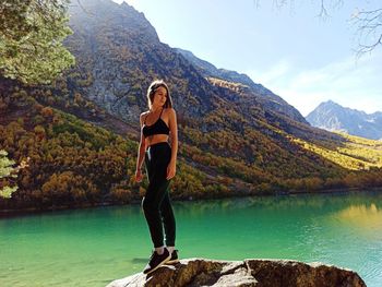 Portrait of young woman standing on rock by lake