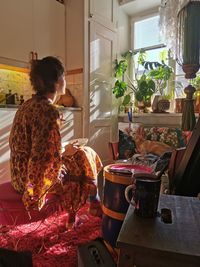 Rear view of woman sitting on table at home