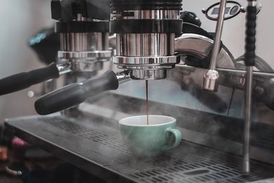 Close-up of coffee pouring from espresso maker in cup