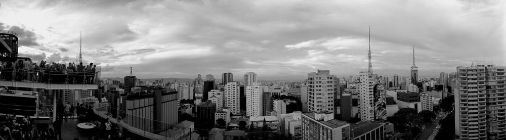 Panoramic view of buildings in city against cloudy sky