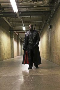 Full length of confident bald man in costume walking at illuminated corridor