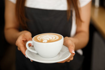 Midsection of woman holding coffee cup