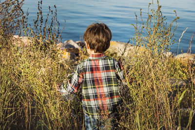 Rear view of boy standing by lake