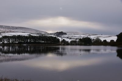 Scenic view of lake by snowcapped mountains against sky