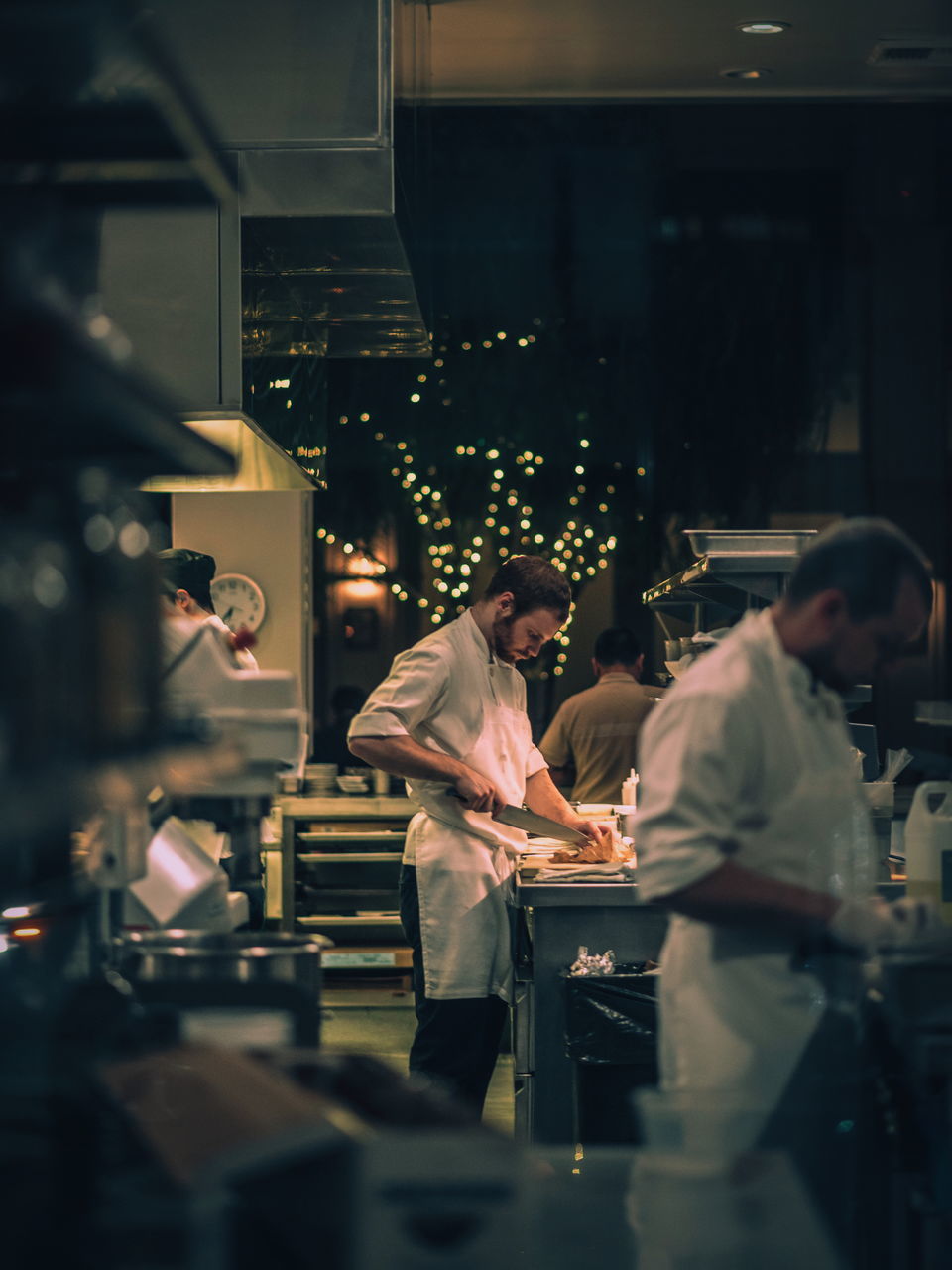 real people, mid adult men, restaurant, indoors, standing, food and drink industry, men, coworker, uniform, young adult, occupation, two people, togetherness, night, bartender, illuminated, food and drink establishment, young women, commercial kitchen, working, teamwork, adult, people