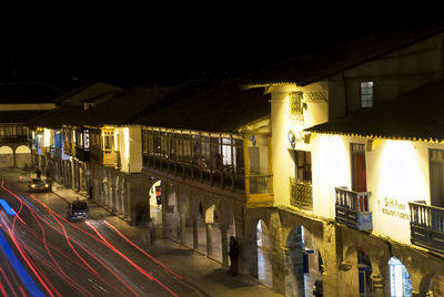 Illuminated street amidst buildings in city at night