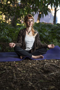 Portrait of woman meditating on exercise mat at park