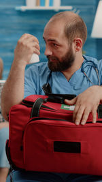 Male nurse carrying bag sitting at clinic