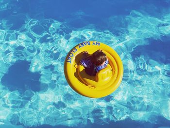 Directly above shot of baby amidst yellow inflatable ring in swimming pool