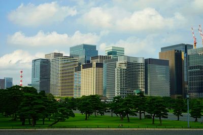 Trees and buildings in city against sky